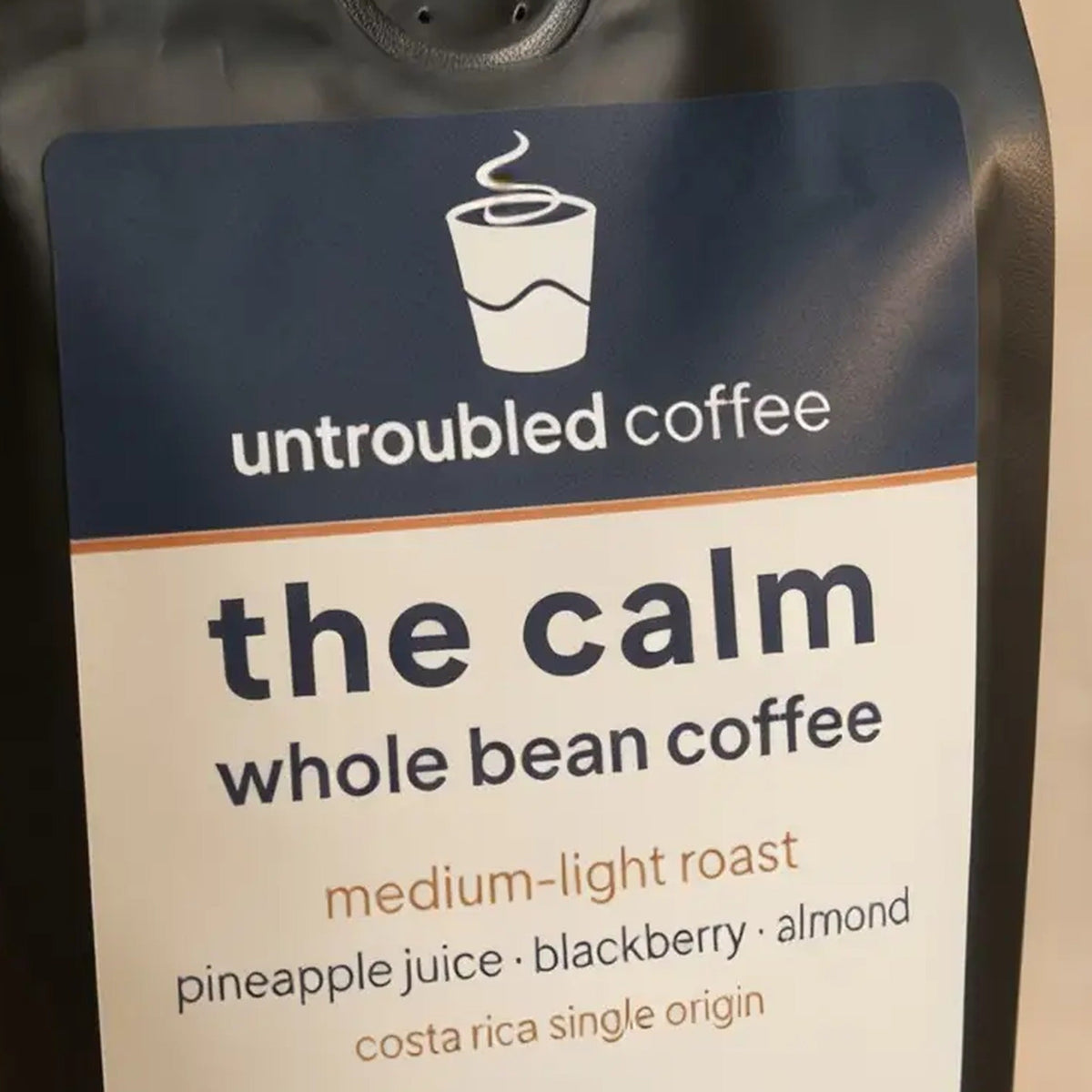 the calm whole bean coffee, black bag with navy and cream label