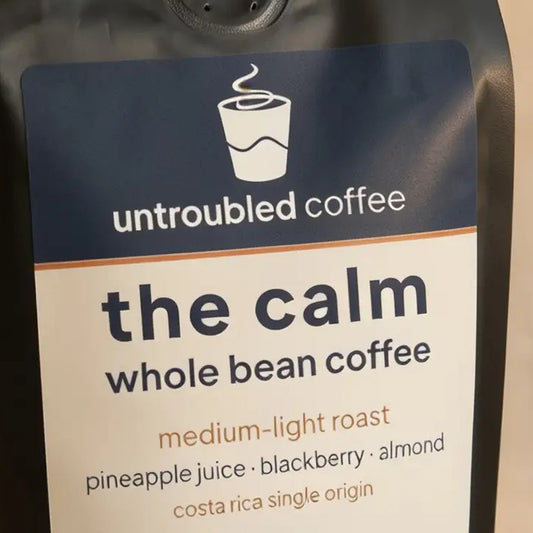the calm whole bean coffee, black bag with navy and cream label